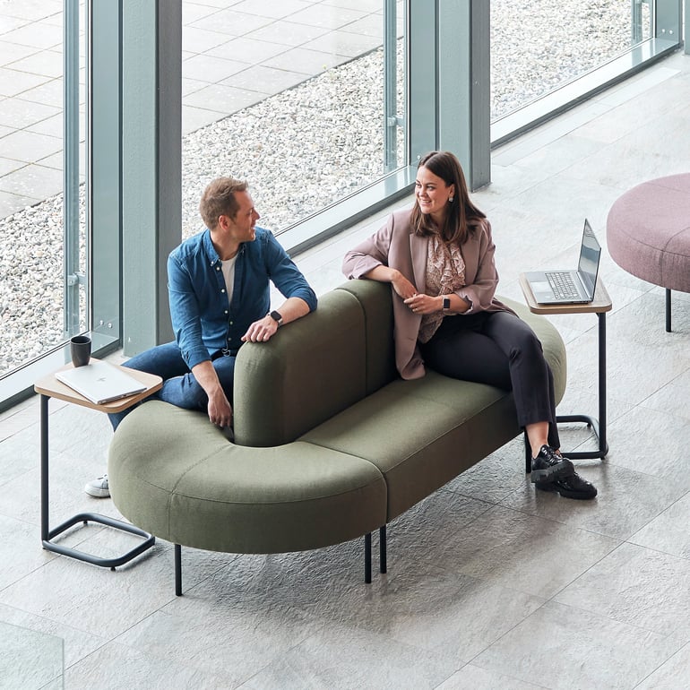 Two people chatting on a large oval sofa