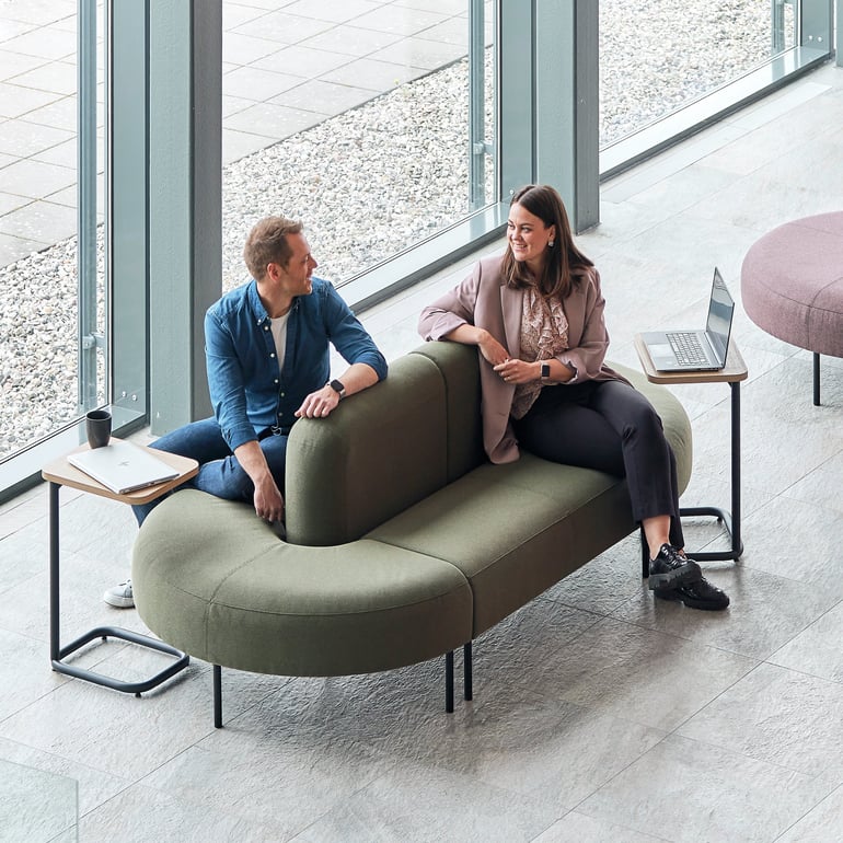 Dvije osobe sjede i razgovaraju na dvostranoj sofi ovalnog oblika