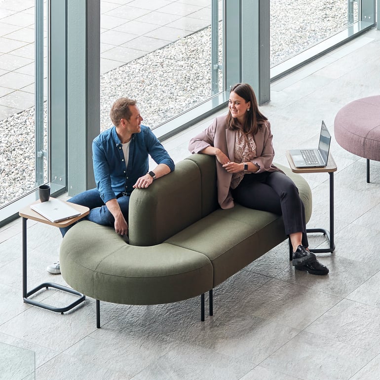 Dvije osobe sjede i razgovaraju na dvostranoj sofi ovalnog oblika