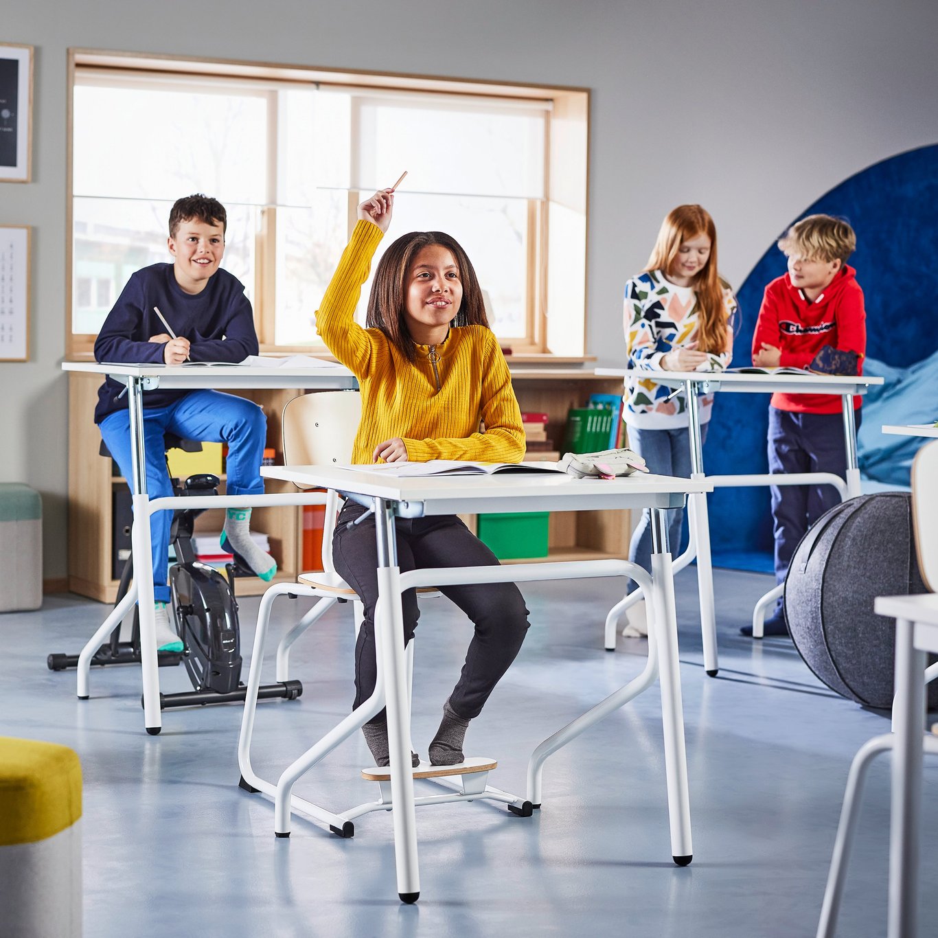 Lapsia luokkahuoneessa oppilaspöytiensä ääressä.
