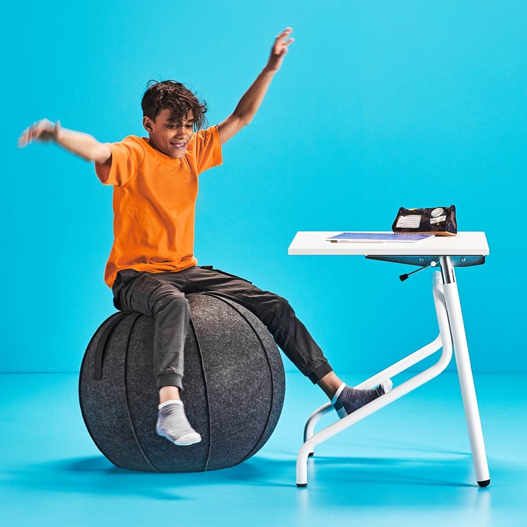 Boy sitting on a Pilates ball and trying to balance