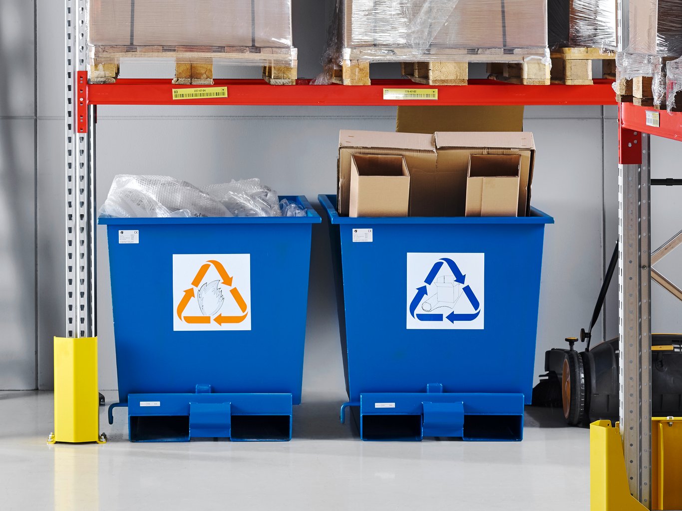 Blue tipping skips used for recycling underneath pallet racking