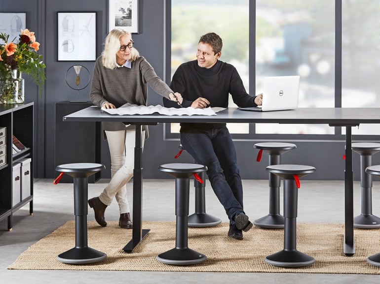 Two people standing at a sit-stand conference table