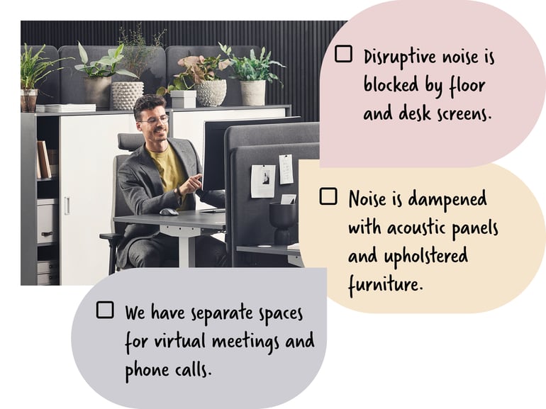 An employee sitting at a desk in an office with pot plants