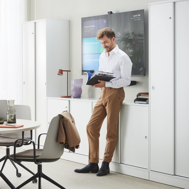 Man stood in a meeting room reading a brochure 