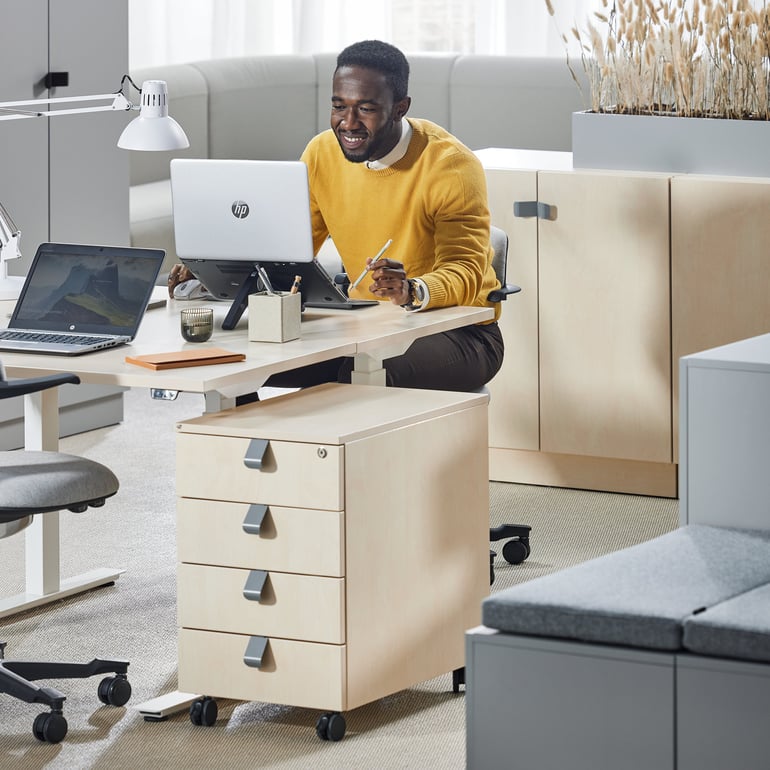 En person som sitter vid sitt skrivbord och arbetar med sin dator