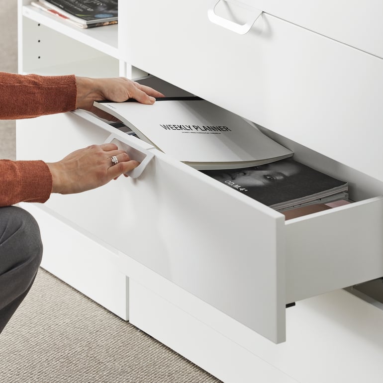 Person placing a brochure into office storage drawer