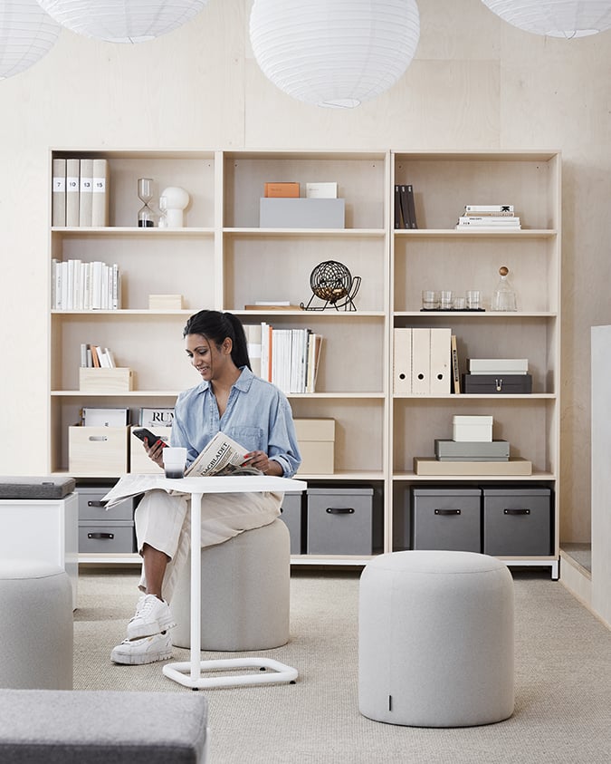 Frau sitzt im Büro und liest eine Zeitung