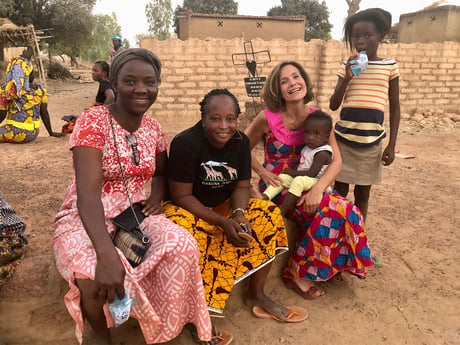 Adults sit with children in an African village