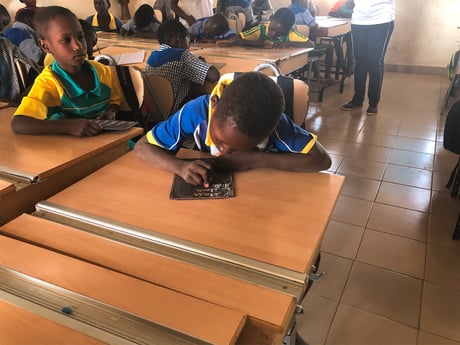 En dreng koncentrerer sig ved sit skrivebord fra AJ Produkter, på en skole i Burkina Faso.