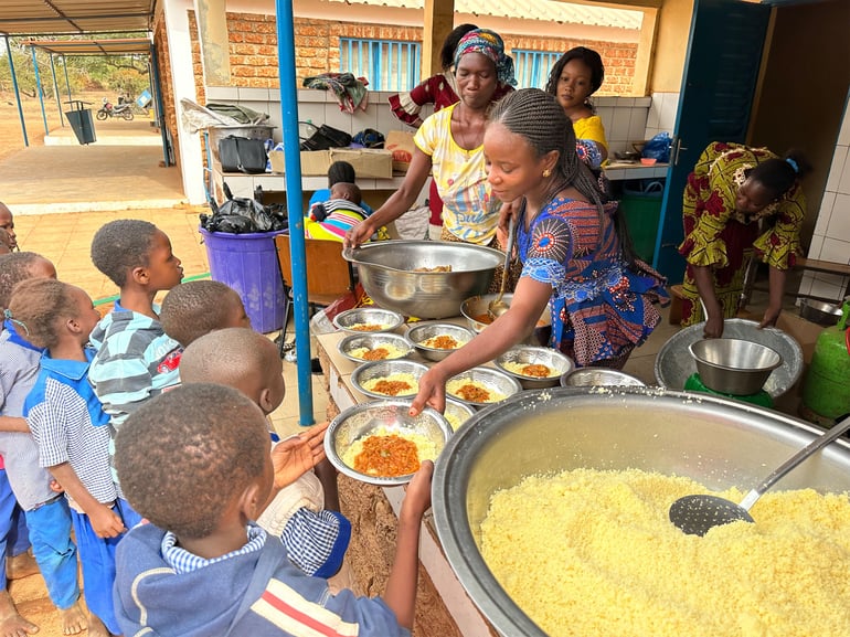 Skolebørn står i kø til frokost i en landsby i Burkina Faso