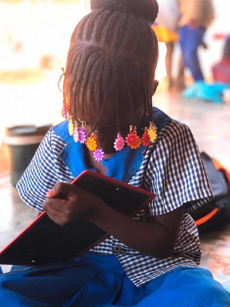 En pige med små fletninger i håret koncentrerer sig på en skole i Burkina Faso