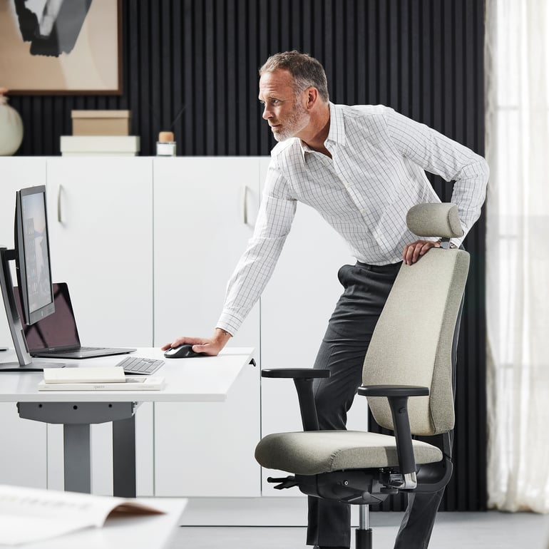En mand står lænet ind over sit skrivebord og bruger musen 