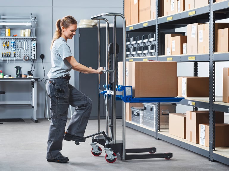 woman using a stacker in a warehouse to lift heavy boxes