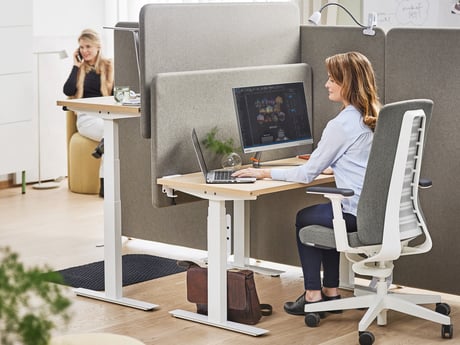 Eine Frau sitz im Büro und arbeitet an ihrem Laptop
