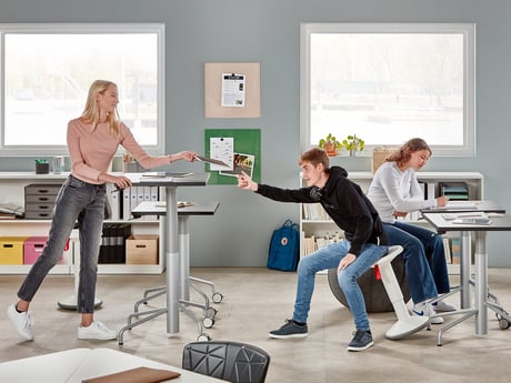 barn som är i ett klassrum fyllt med bord och aktiva skolmöbler