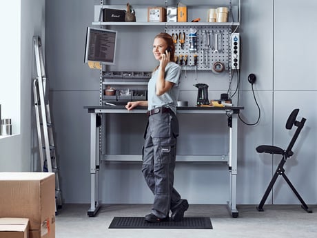 A girl standing on a mat in front of a height adjustable work table.