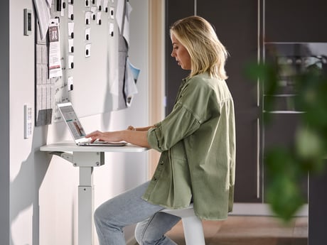 Woman working on a laptop at a desk in a home office space