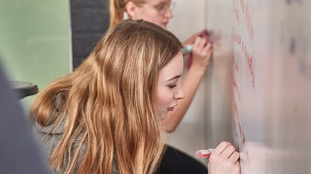 Students writing on whiteboards