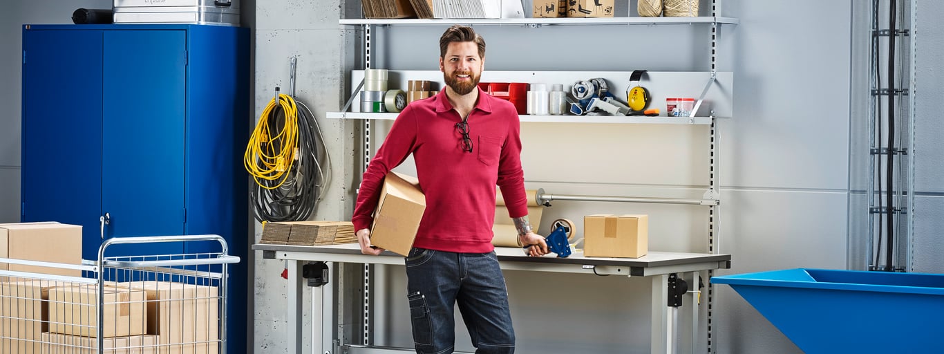 A man standing in front of a sit-stand workbench