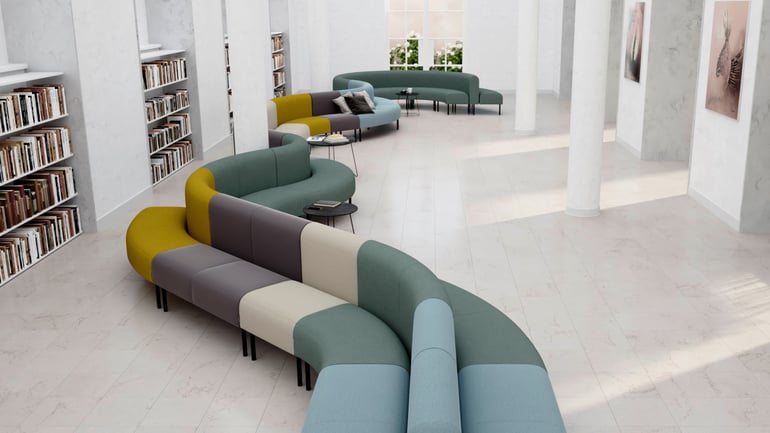 Pitkä värikäs sohva, joka mutkittelee suuren tilan läpi