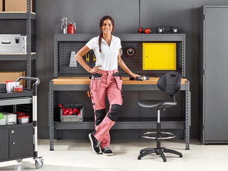 Woman standing next to a factory chair in front of a workbench