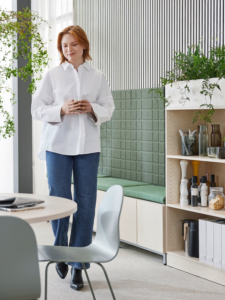 En kvinde står i en kantine med QBUS møbler
