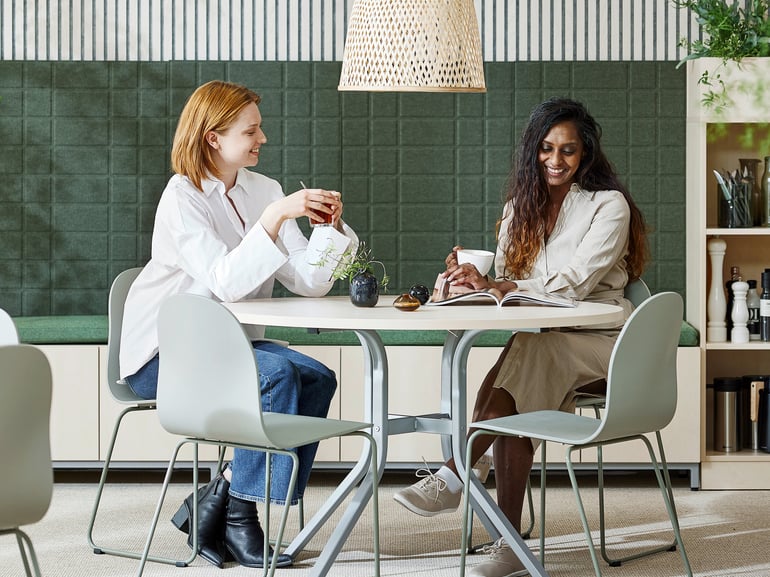 Dvi moterys kalbasi prie valgomojo stalo