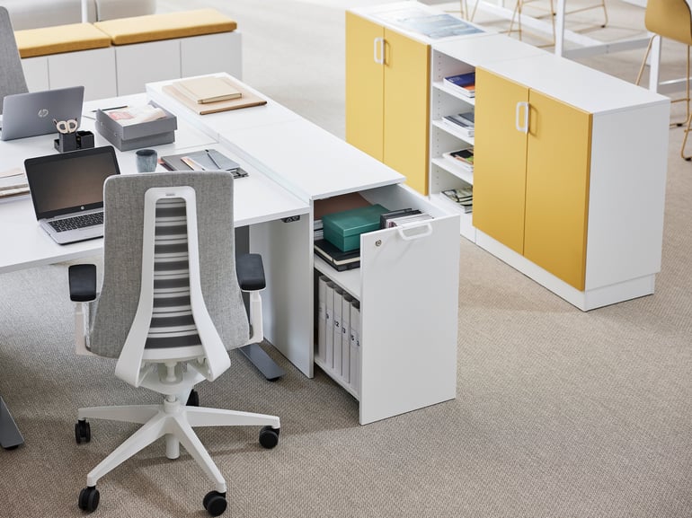 Desk space with an office chair and pull-out cabinet on the side and shared yellow cabinets.