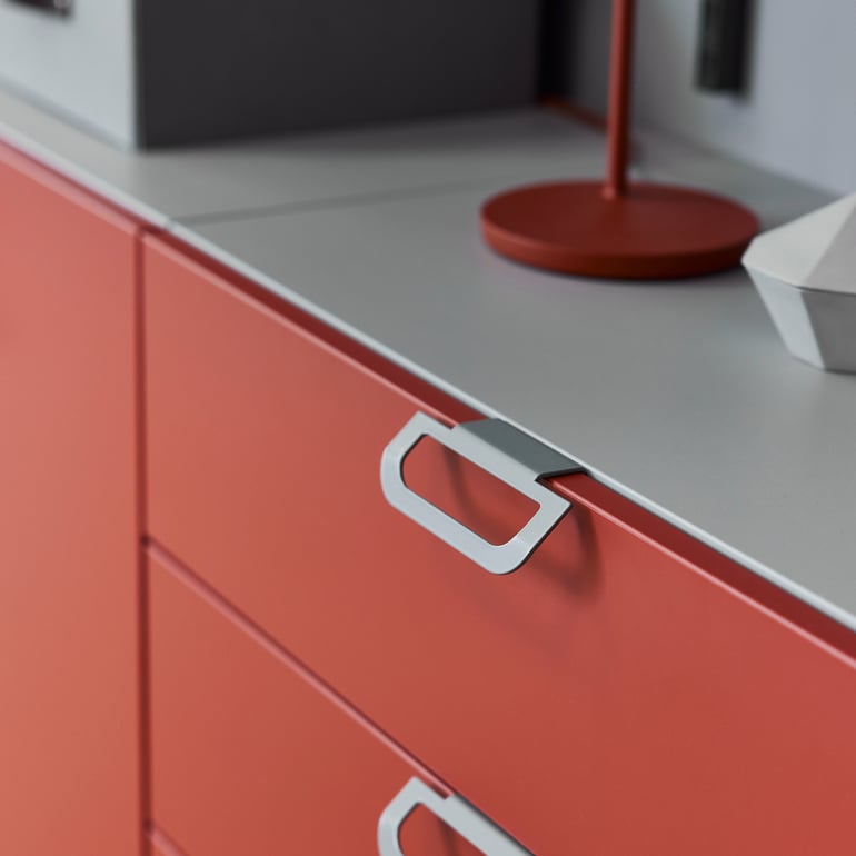 Close up of handles on a red chest of drawers