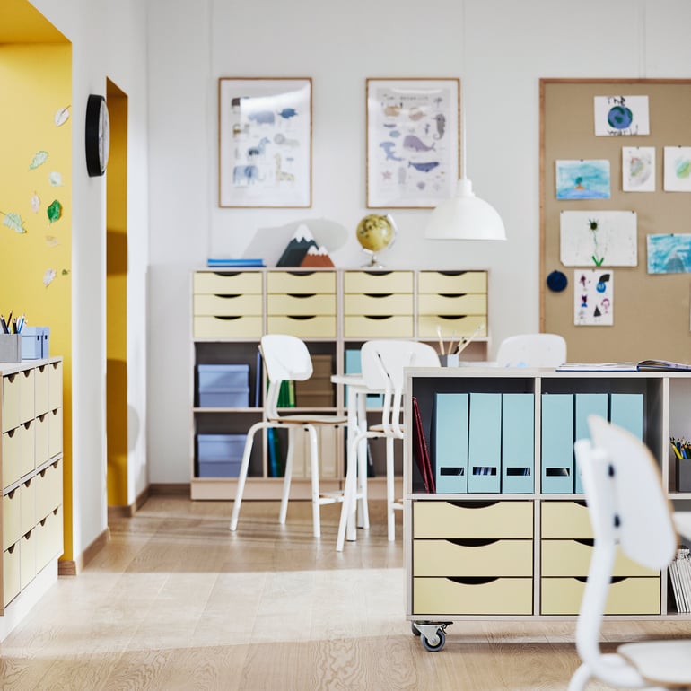 Et lyst klasseværelse med indretning i træ, gul og blå