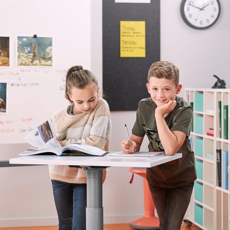 Två skolbarn står vid ett elevbord