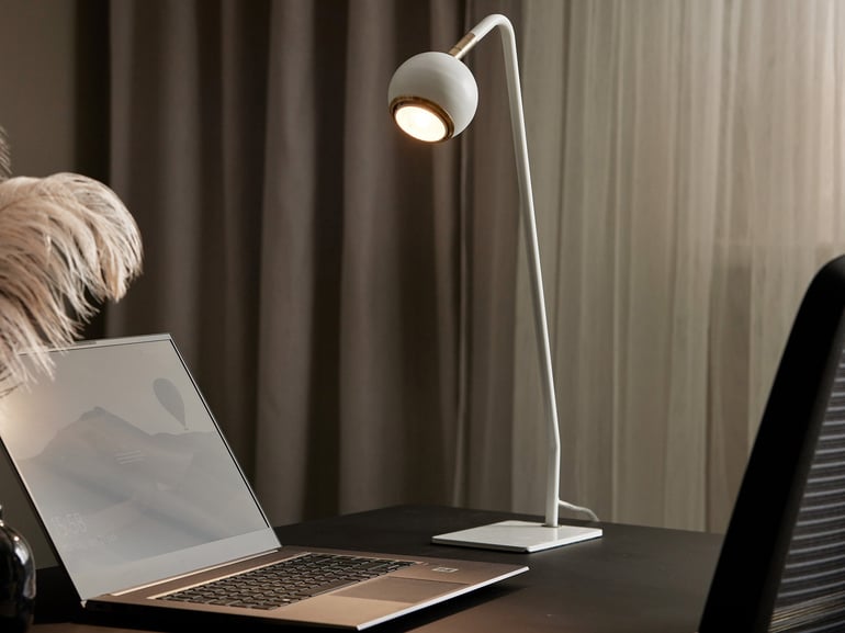Skrivebord med computer og hvid skrivebordslampe på siden