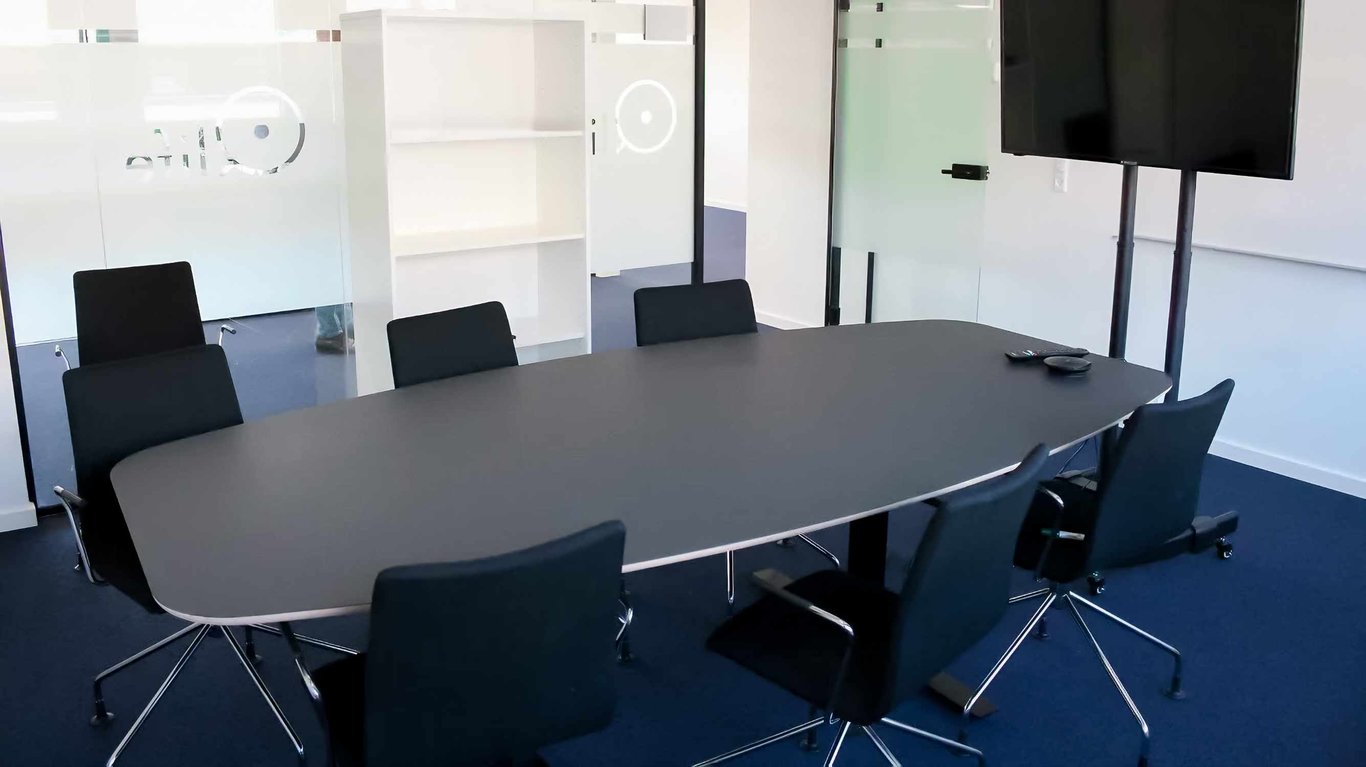 Mødelokale hos Qlife med et flot mørkt mødebord og sorte konferencestole